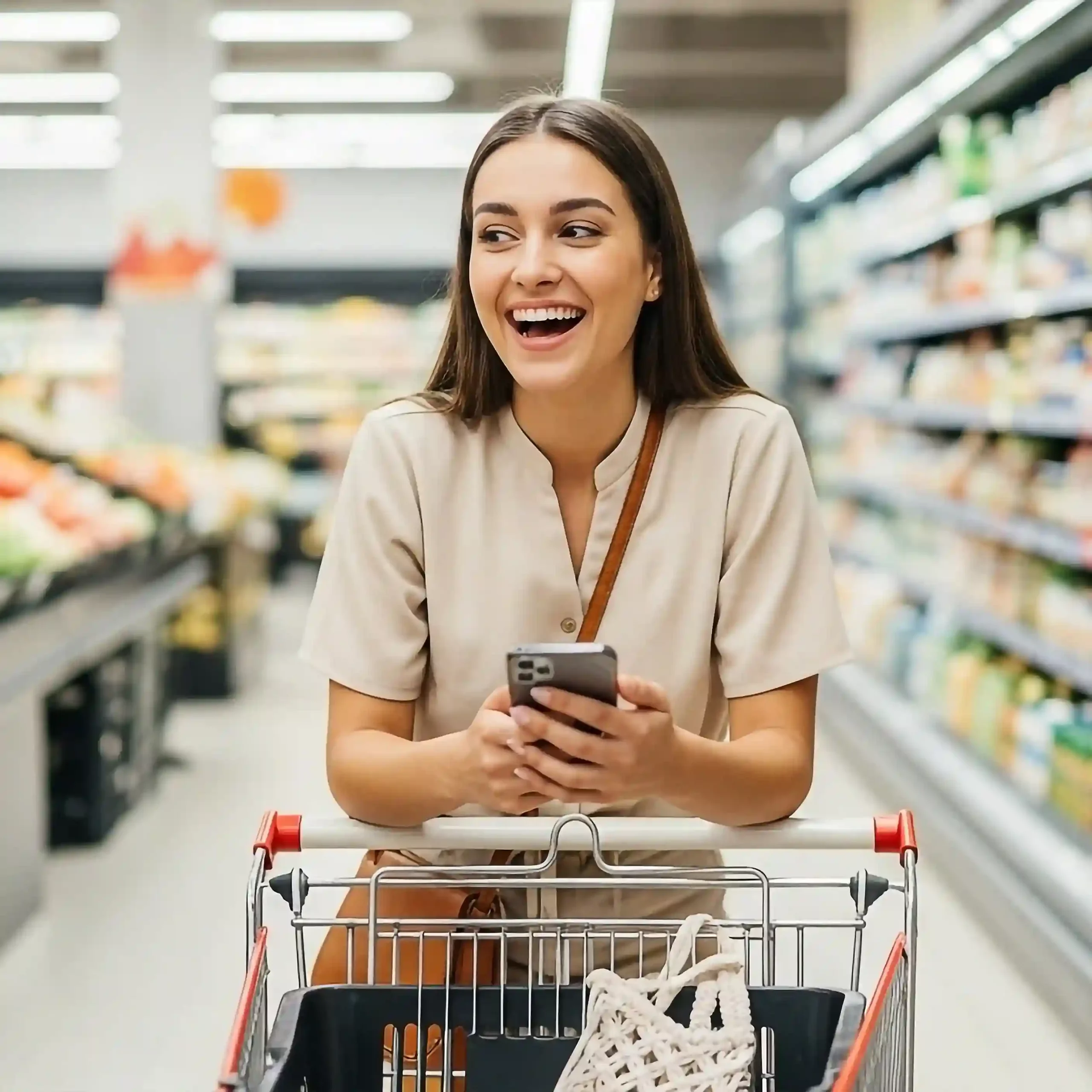 Customer checks her mobile phone in a grocery aisle, representing Indosoft’s ability to merge retail engagement with retail communication technology. A shopper uses Indosoft retail software on her phone to contact retail services, showcasing connected communication and seamless customer experience.