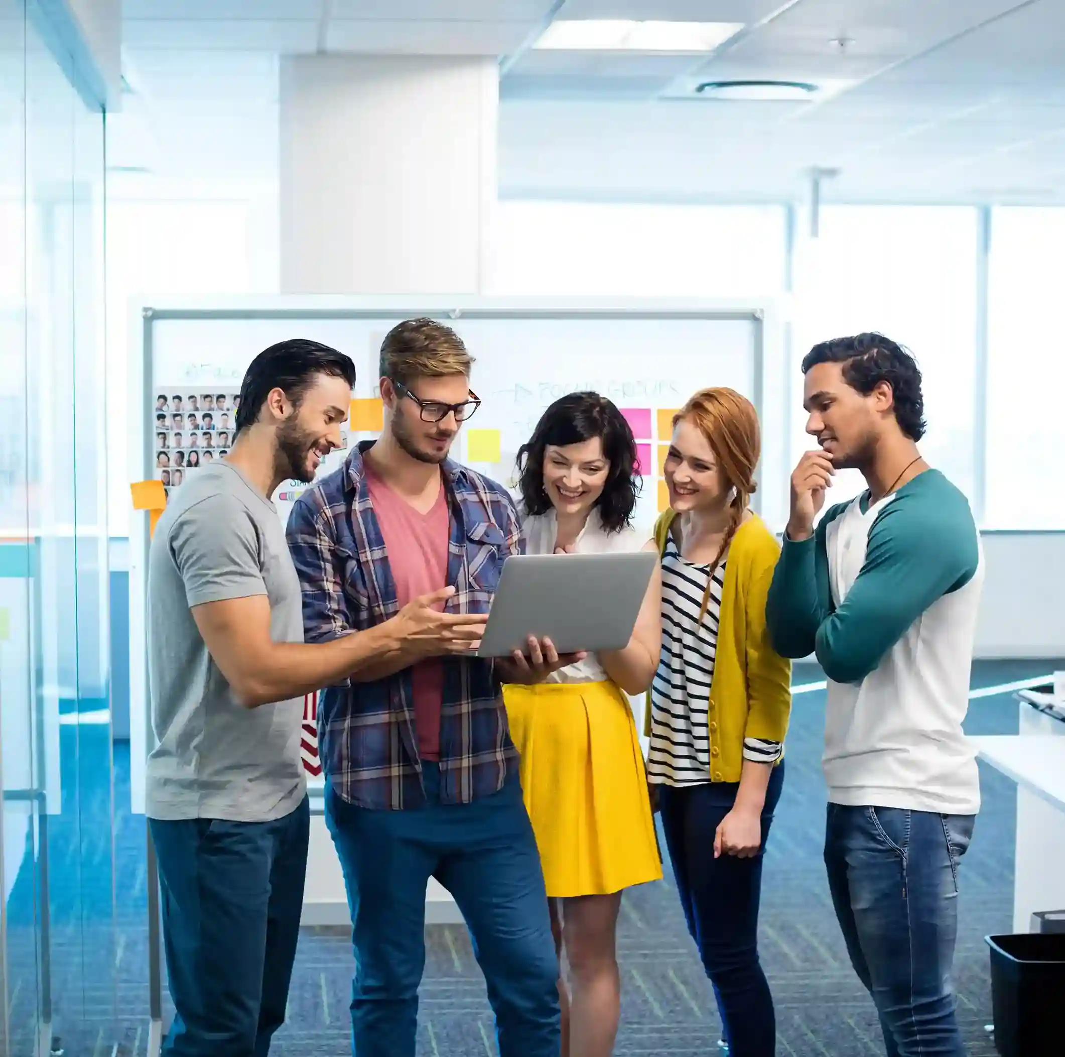 Indosoft employees brainstorming together in a modern workspace, reflecting a culture of creativity and collaboration. Creative Indosoft team collaborating over a laptop in the office, symbolizing innovation and teamwork in AI-driven communication.