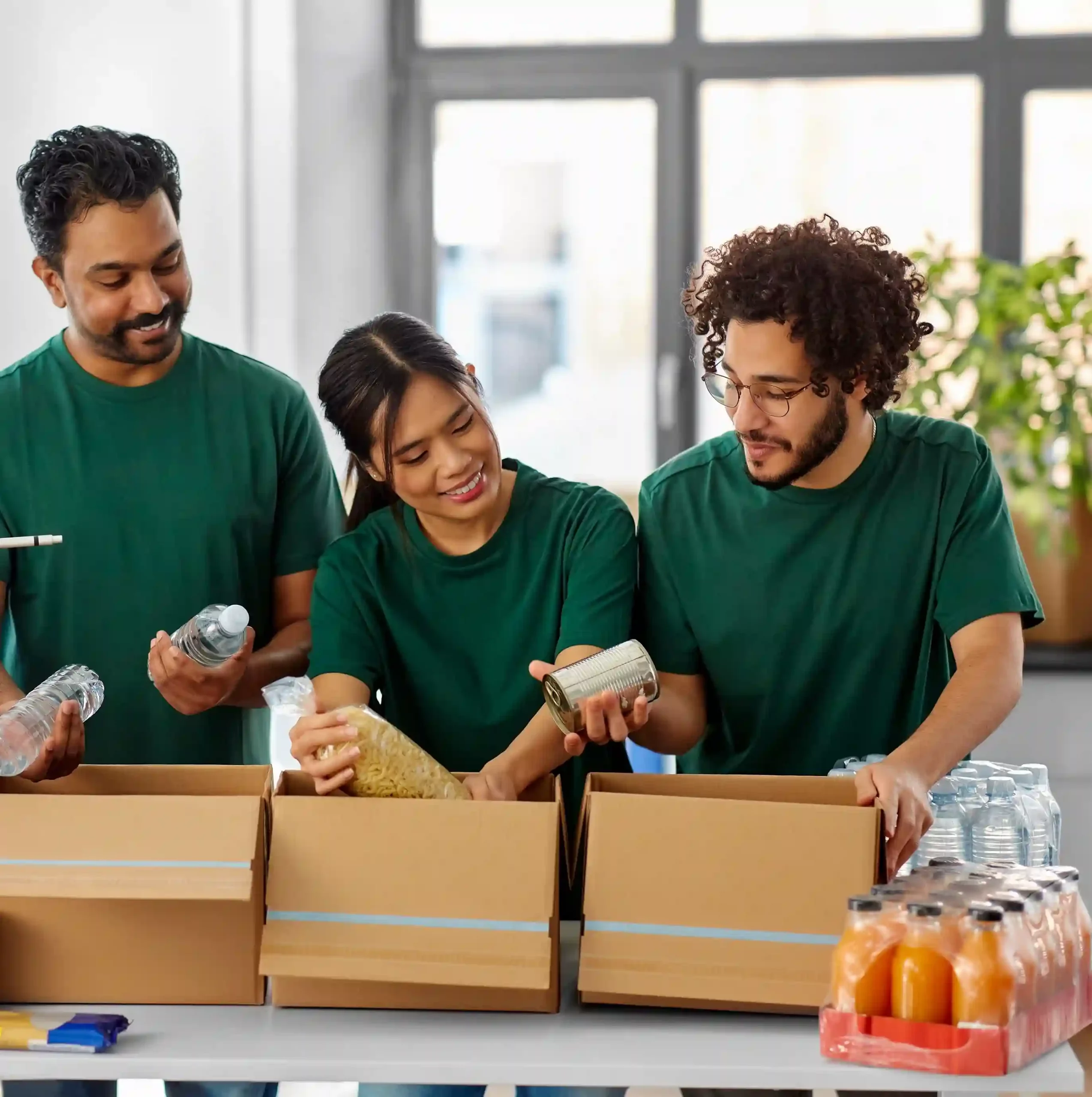 International team of volunteers smiling while preparing food packages, showcasing collaboration for a common cause. Group of diverse volunteers packing food boxes and collaborating at a refugee assistance center to support their mission.