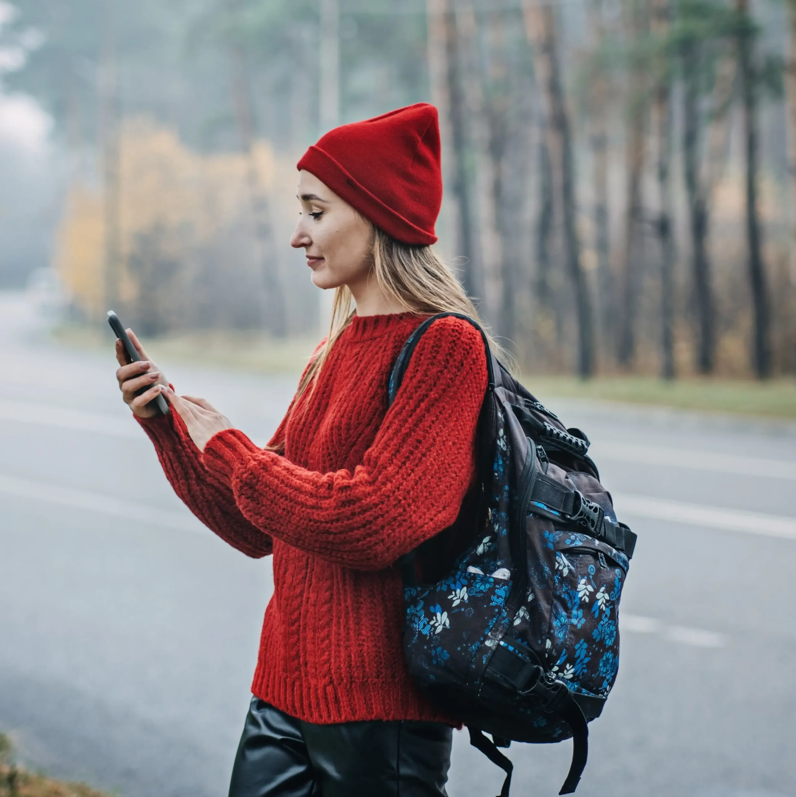 Customer checks her mobile phone in a grocery aisle, representing Indosoft’s ability to merge retail engagement with retail communication technology. Woman using her smartphone while standing outdoors with a backpack