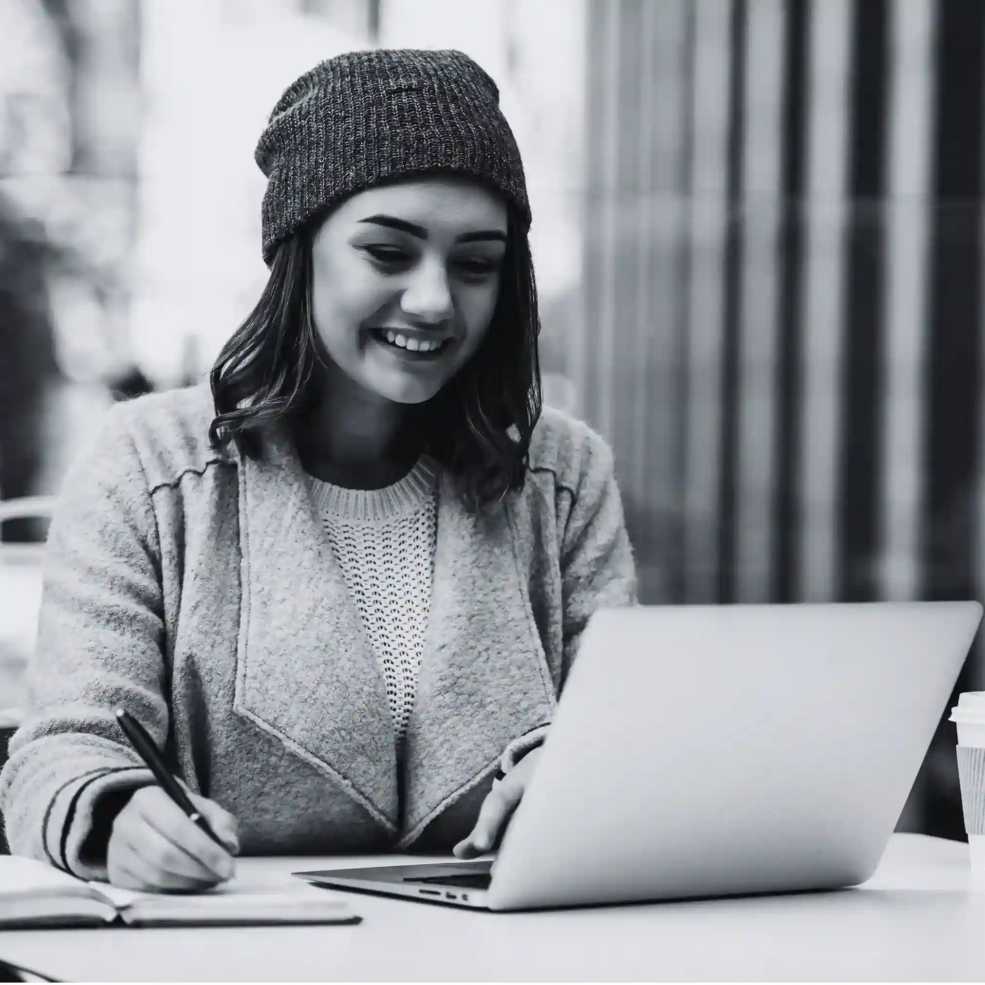 Featuring a professional engaged in both typing and writing, the image symbolizes Indosoft’s enhanced routing intelligence, automation strength, and scalable architecture that outperform SnapCall. Young professional writing in a notebook while using a laptop, representing the move from SnapCall to Indosoft for more scalable communication.