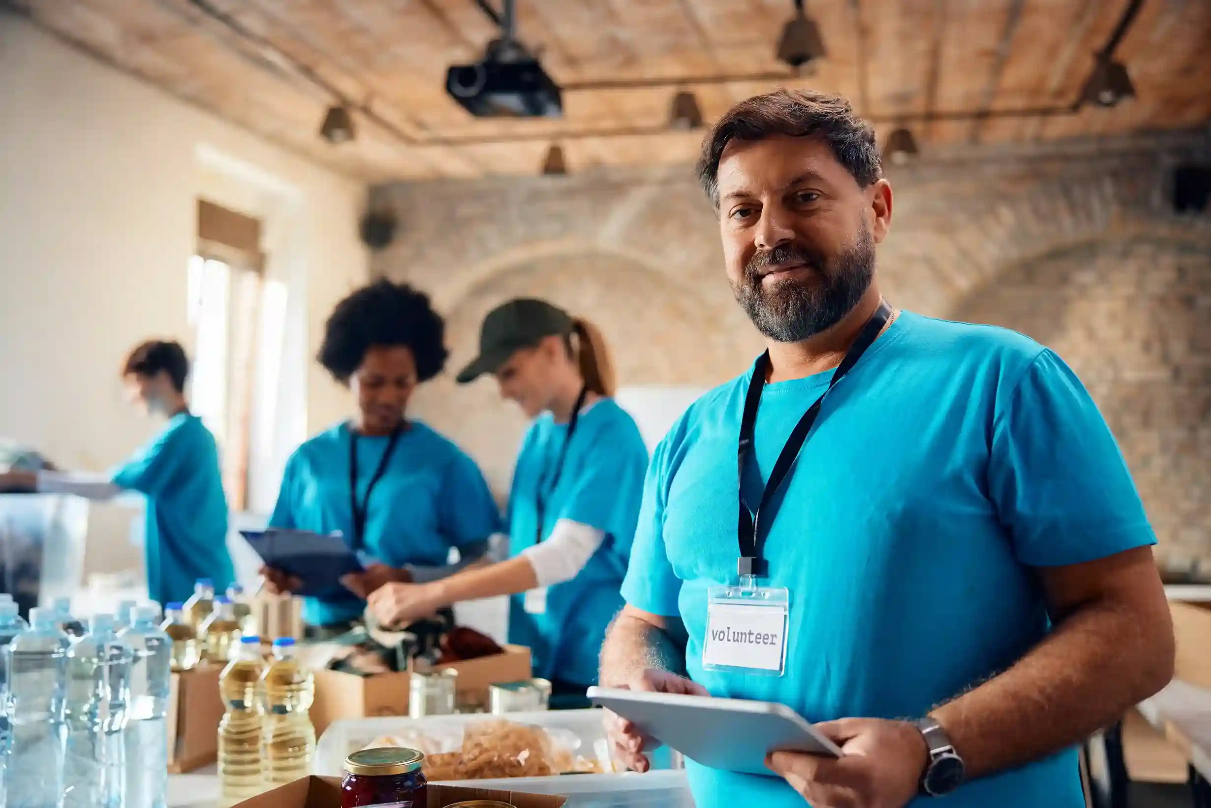 Smiling food bank volunteer using a touchpad to stay connected with donors and supporters across multiple channels. Volunteer using a digital tablet to engage with community members and coordinate outreach at a local food bank.