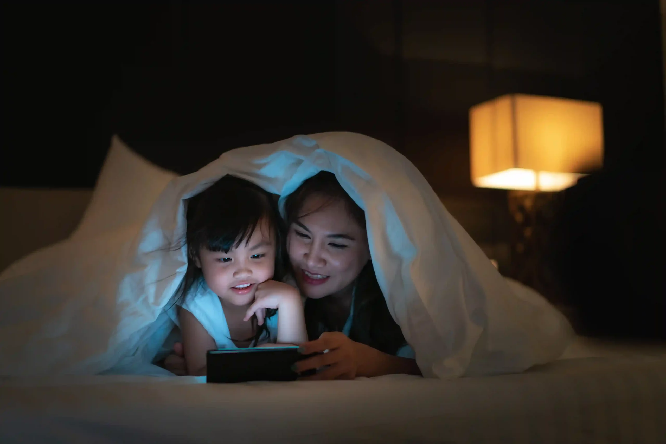 A mother receives a late delivery alert on her phone while spending time with her child, illustrating how Indosoft surfaces after-hours calls without requiring constant system monitoring. A parent checks a phone late in the evening while a child sits nearby, responding to a delivery notification that arrives outside normal hours, reflecting how Indosoft keeps teams informed of after-hours calls.