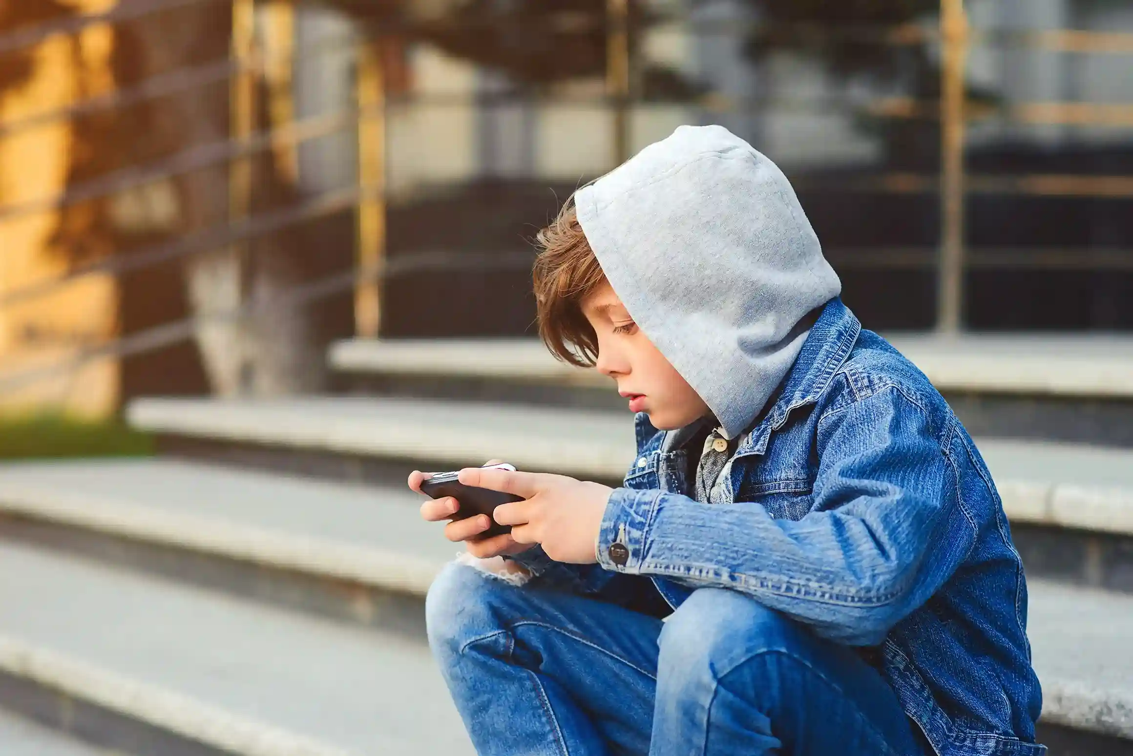 A young user receives a carefully filtered notification on a mobile device, mirroring how Indosoft sends call alerts only to authorized roles to avoid noise and distraction. A child quietly focuses on a phone as age-appropriate notifications appear, reflecting how Indosoft routes alerts only to the right recipients based on defined roles and responsibility levels.