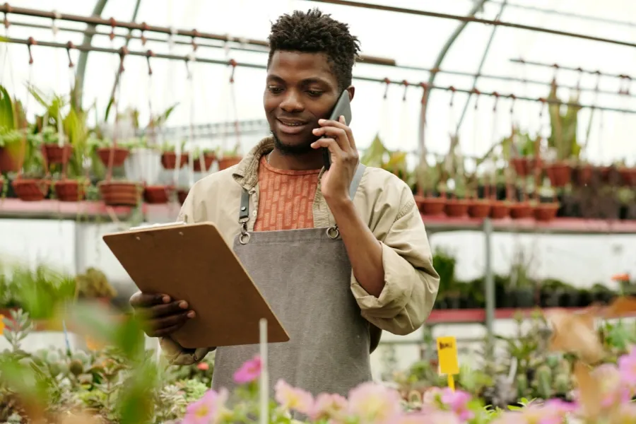 Florist answering a redirected customer call on his mobile phone. Flower shop owner taking a customer order on a mobile phone after the call was instantly redirected from a shared database.