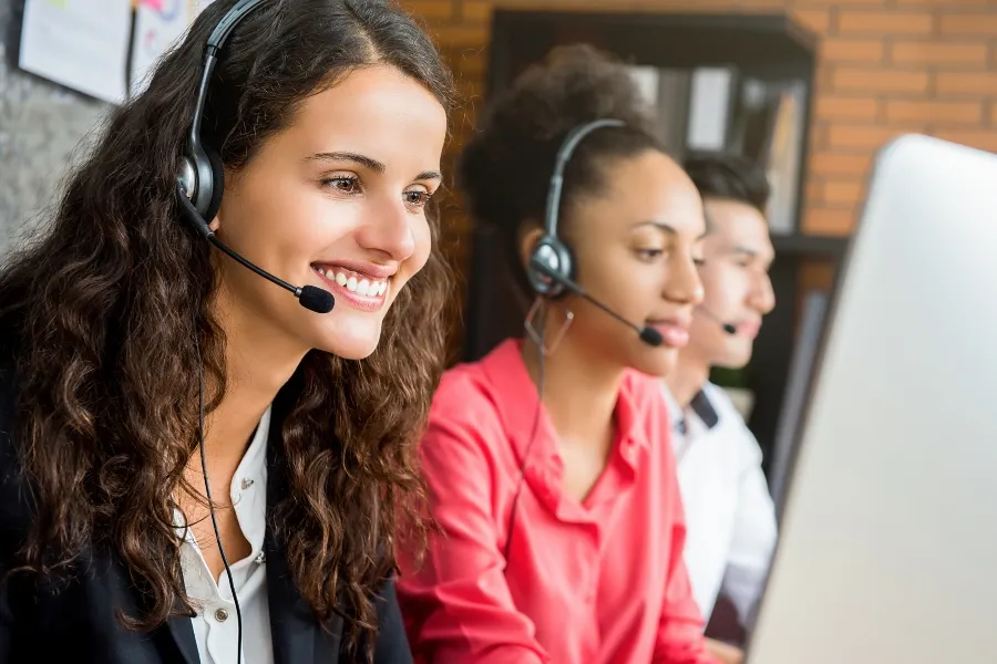 Support agents on headsets managing calls through multi-device routing. Call center agents wearing headsets and assisting customers, representing flexible call routing to alternate teams or devices.
