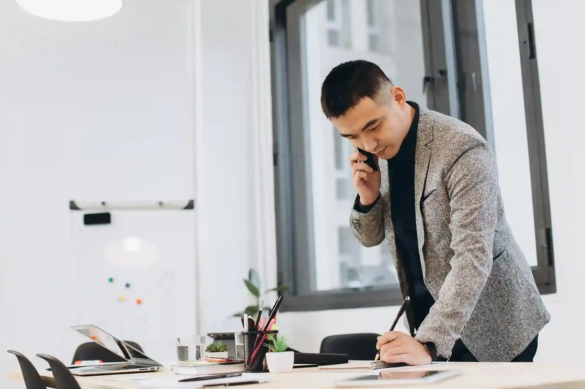 While speaking on the phone, a business professional uses mute to search through materials at his desk, maintaining control and professionalism throughout the call. An executive quietly mutes an active call while reviewing documents and taking notes, staying composed before continuing the conversation with confidence.