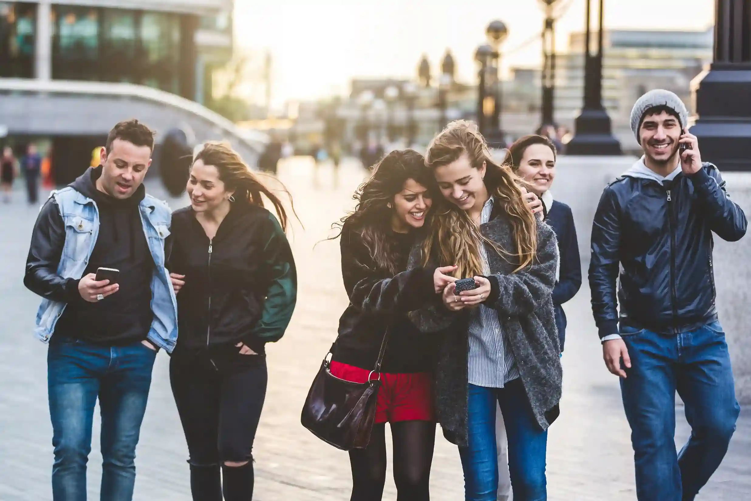 Friends compare messages on their phones during a city walk, noticing distinct caller IDs that clearly reflect different campaign messages sent by a business. A group of friends walk through the city while checking their phones, easily recognizing different caller IDs tied to specific campaigns reaching them at the right moment.