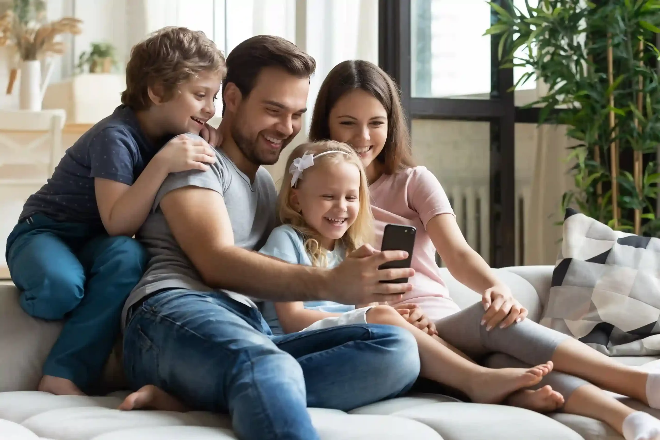 A family smiles while looking at a phone screen, symbolizing how Indosoft makes reviewing call history simple and transparent. A family gathers around a phone, reviewing recent calls together, reflecting how Indosoft centralizes call history into one clear, shared view.