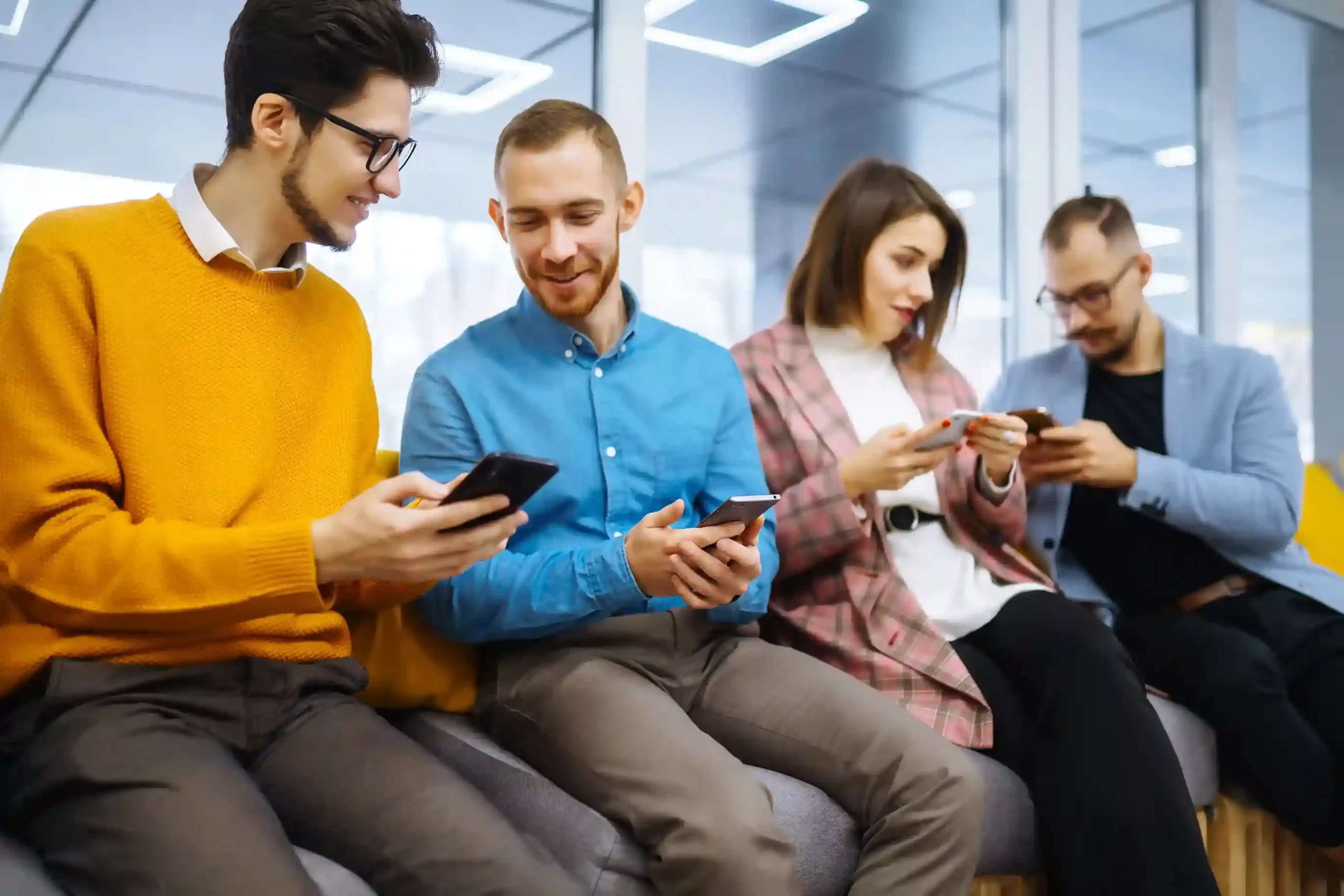 Team members seated together check identical voicemail messages on their devices, reflecting how Indosoft maintains uniform communication using pre-recorded voicemail drops A group of colleagues review the same voicemail on their phones together, showing how Indosoft delivers a single pre-recorded announcement consistently across the entire team.