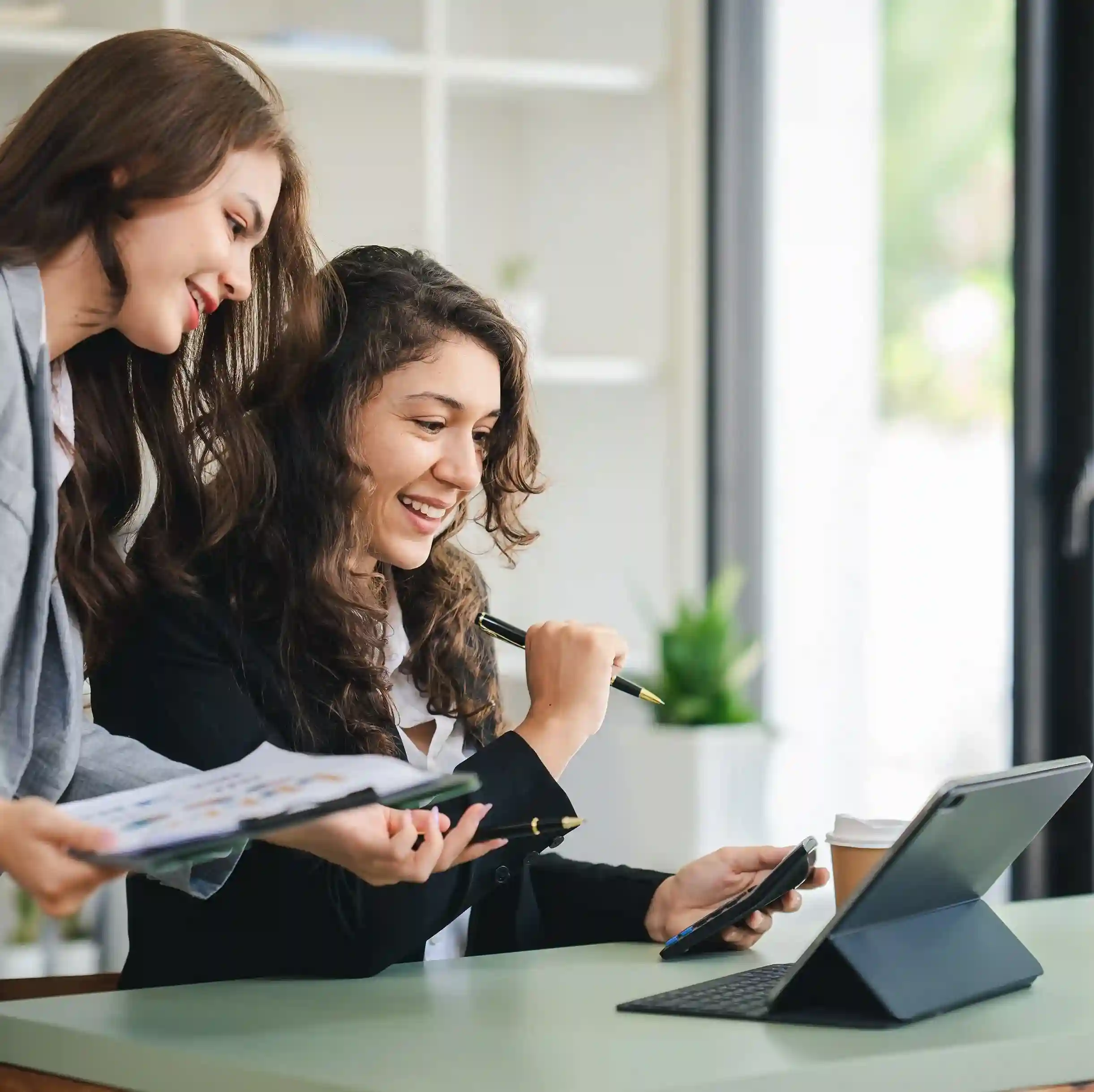 Team members reviewing calls on a tablet and phone, illustrating smart call forwarding. Two colleagues smiling while reviewing information on a tablet and smartphone, representing smart call forwarding that keeps callers connected.