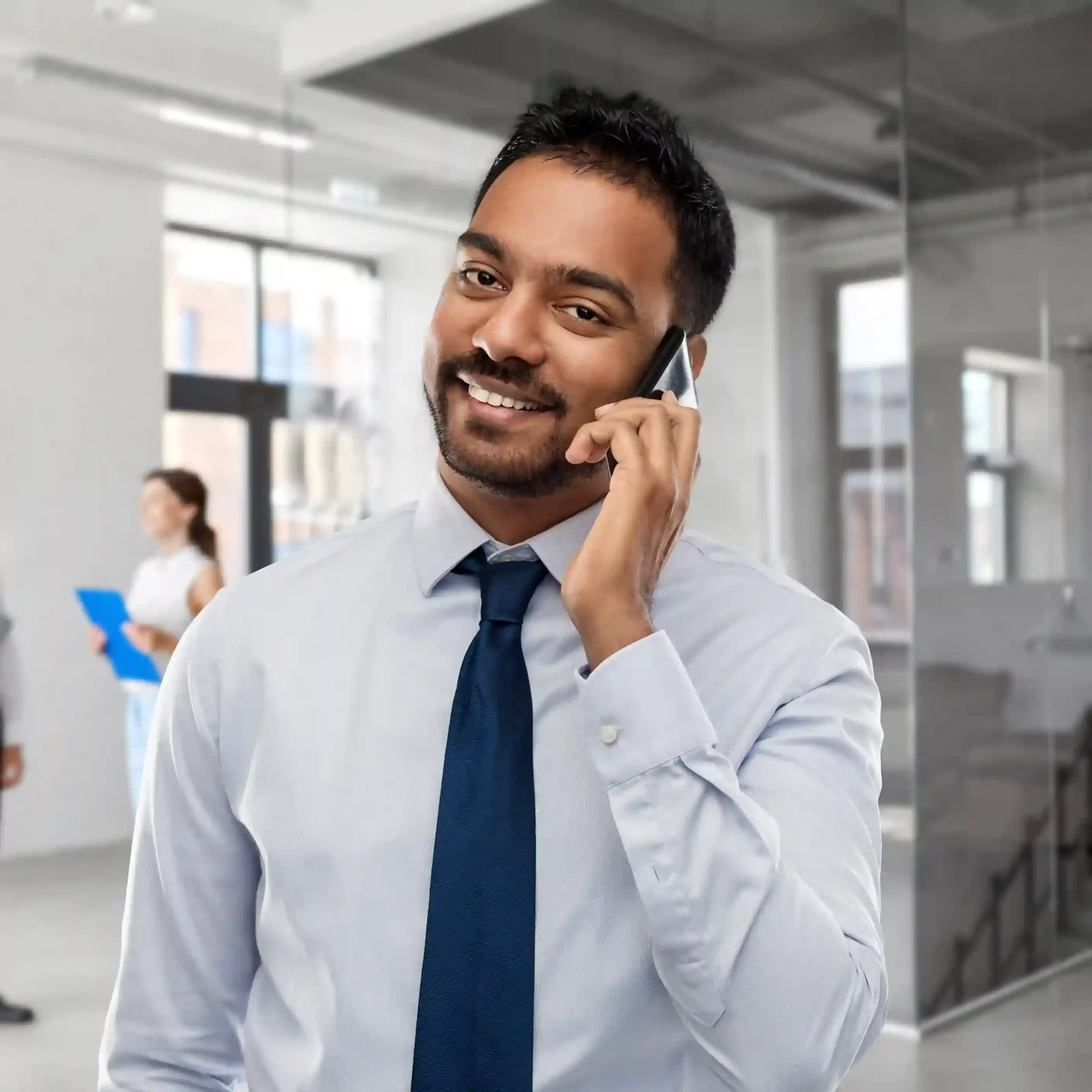 An office professional smiles while handling a phone call, reflecting how a well-crafted greeting prepares callers and reduces uncertainty at the start of every call. A professional confidently answers a call in a modern office, showing how custom greeting messages set a clear and polished tone before the conversation begins.