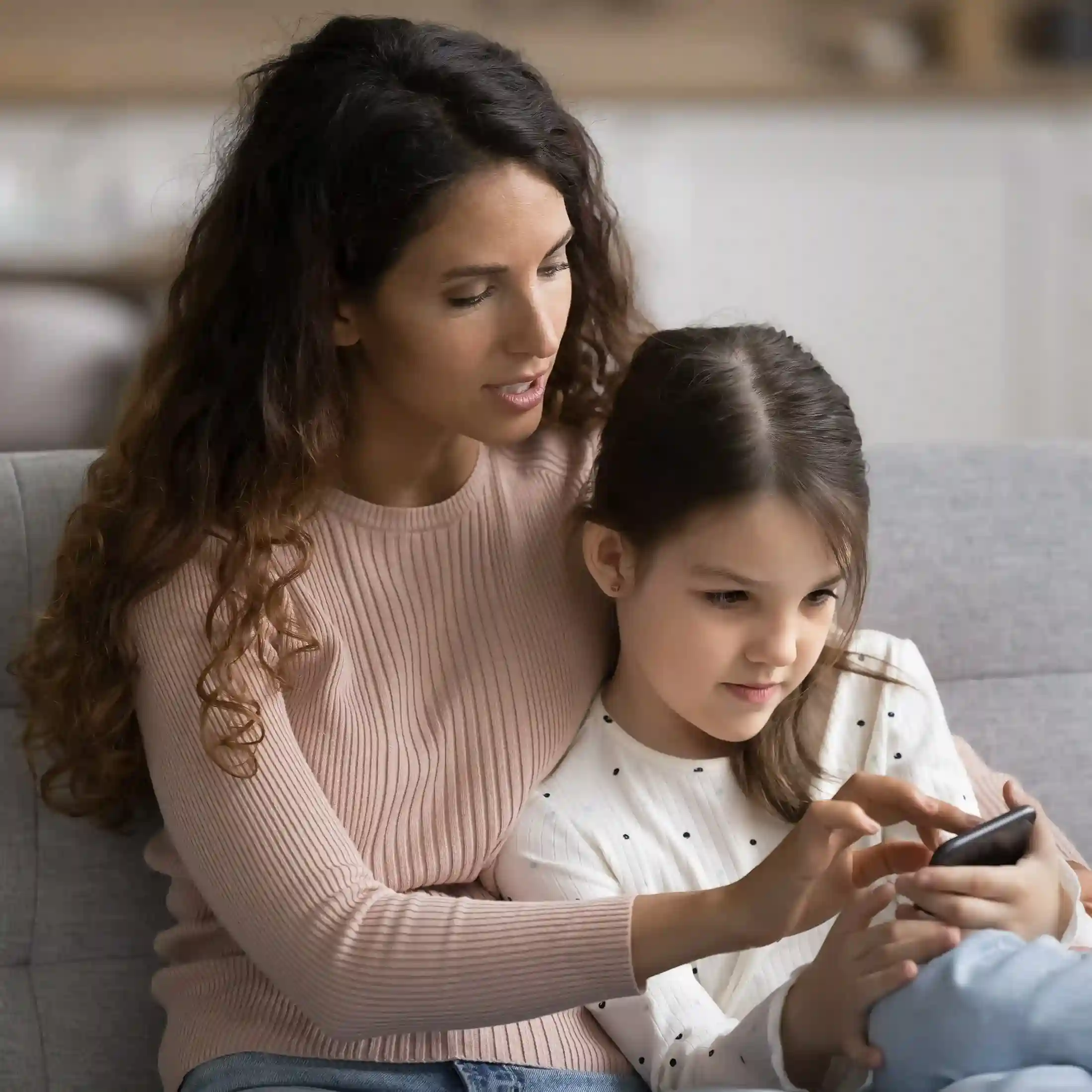 Ring All Devices helps contact centers reduce missed calls by alerting agents across all connected devices, improving response times even when agents are away from their primary workstation Sitting together at home, a parent guides a child while checking an important alert on a phone, reflecting how Ring All Devices ensures critical calls reach agents wherever they are.