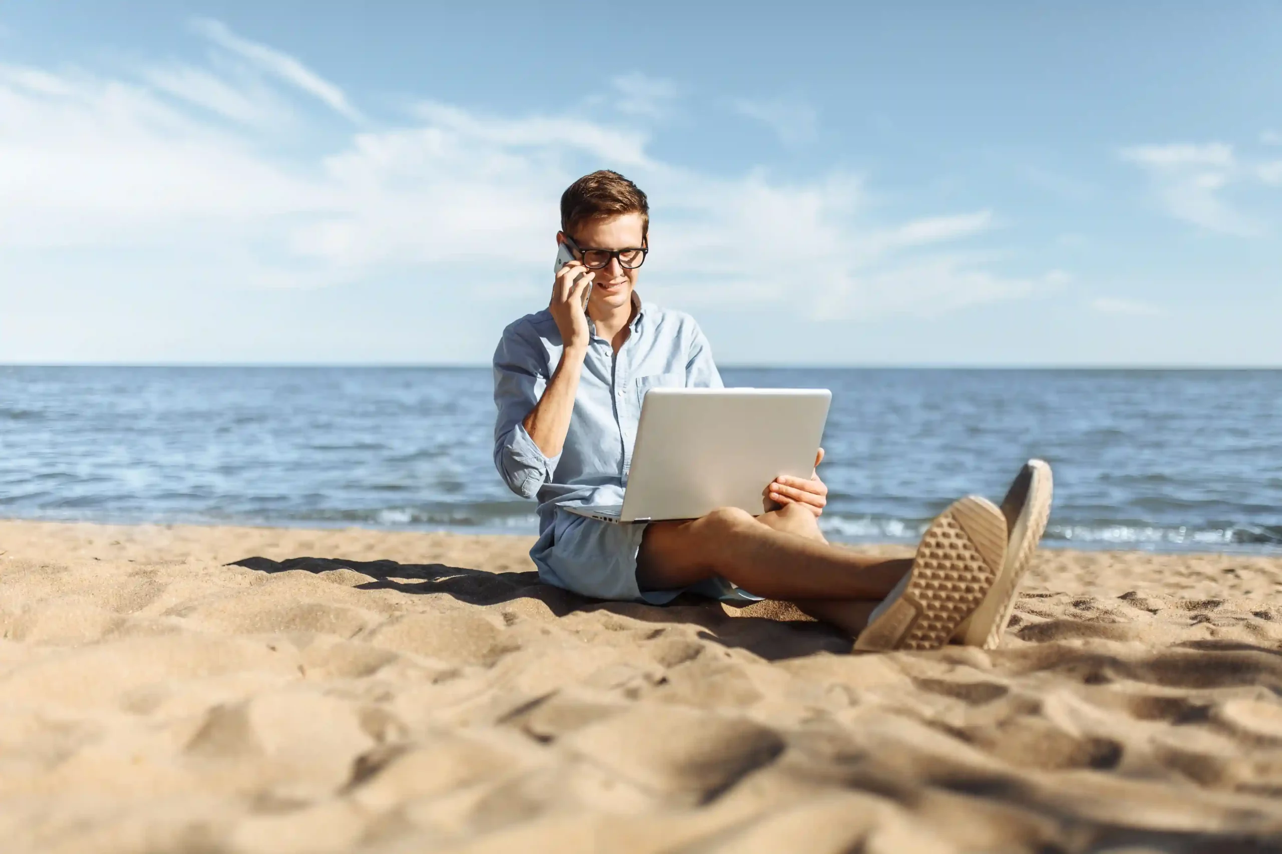 An agent balances work and mobility by accessing customer information on a laptop and initiating a call through an integrated business application with a single action. A professional reviews customer details on a laptop by the beach and places a call directly from a connected CRM record, showing how integrated systems keep work moving anywhere.