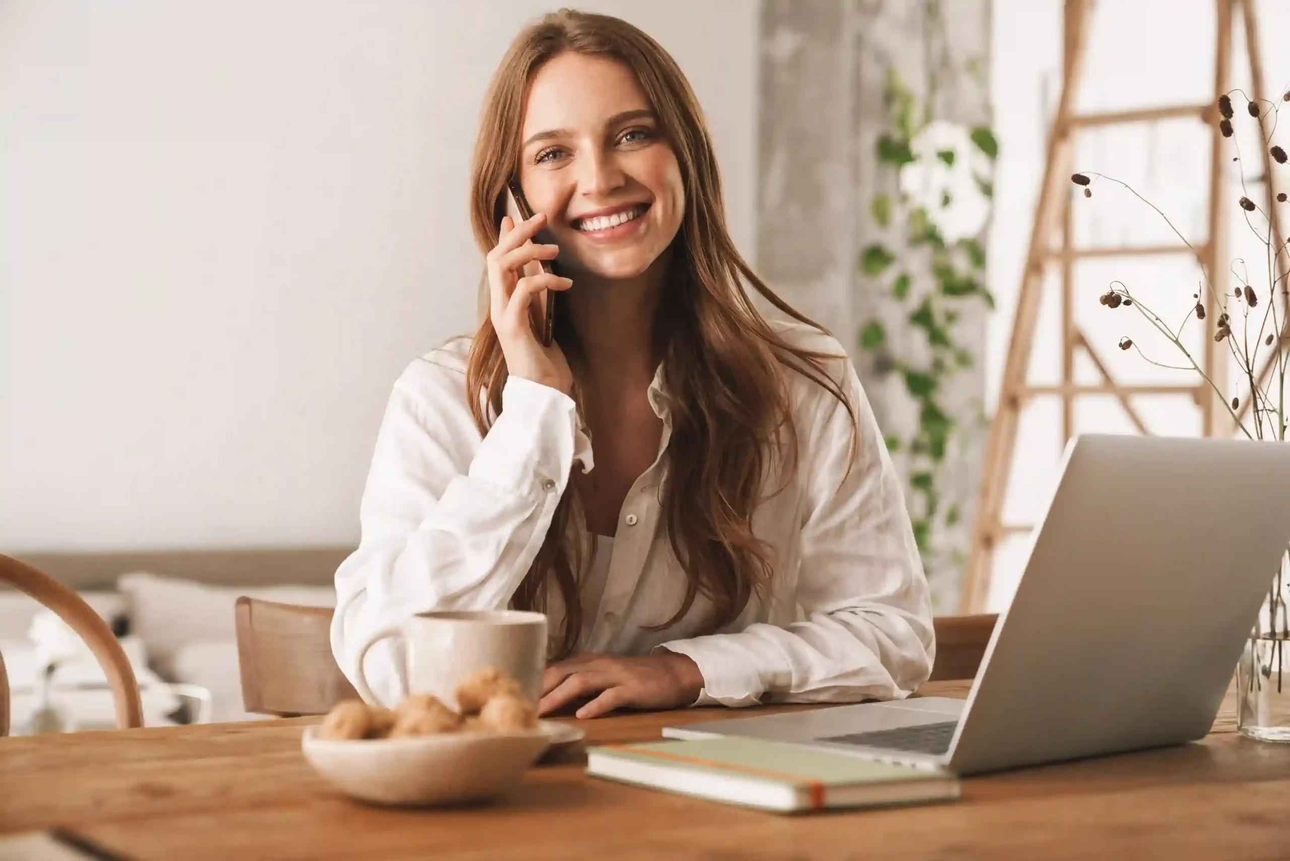 A business user handles a phone call calmly from her workspace, knowing greeting messages have already guided the caller and simplified the conversation. A professional smiles while answering a call at her desk, confident that callers already received key information through a greeting message before the conversation began.