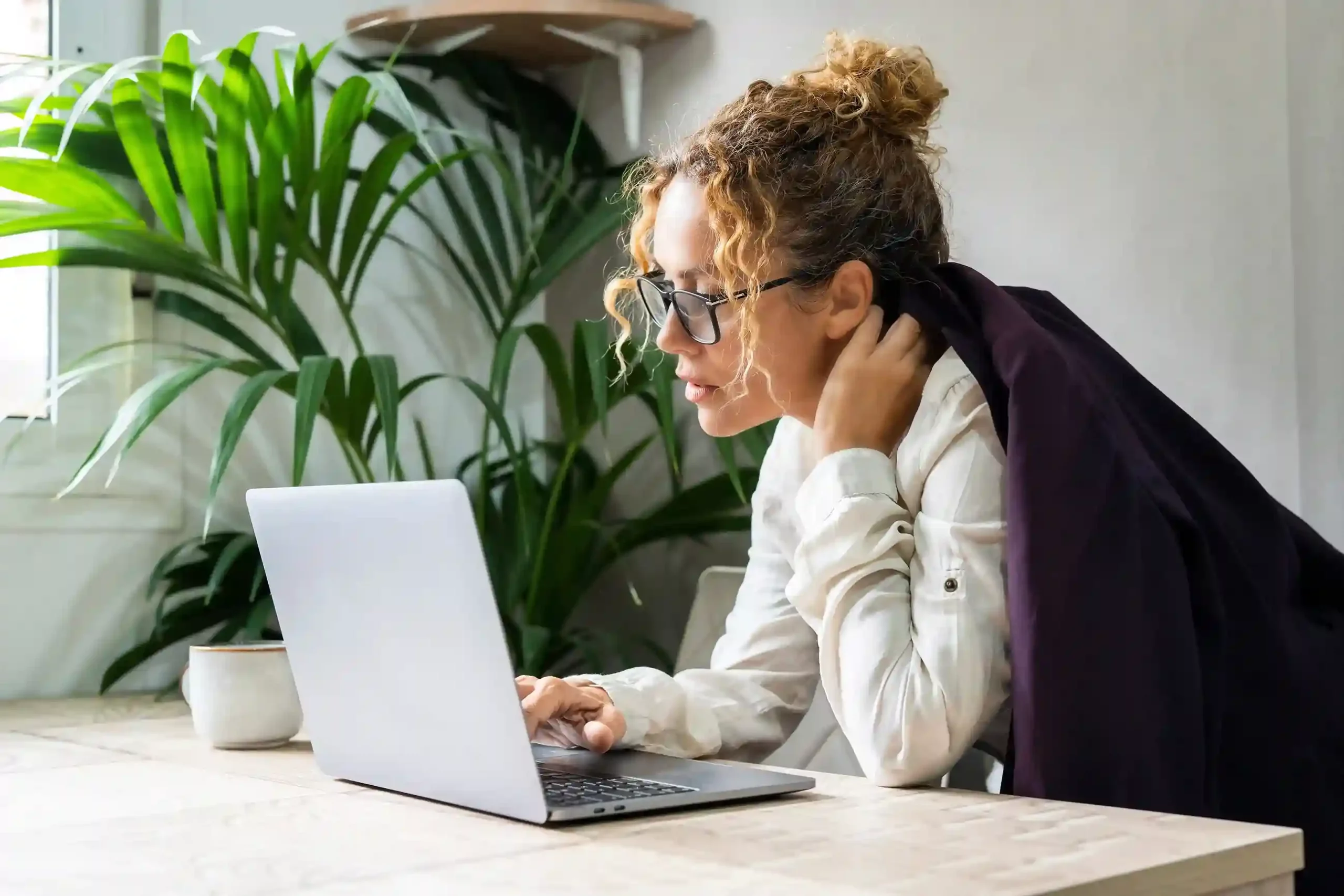 Focused at her desk, a supervisor accesses selected contact records on her laptop, reflecting how Indosoft applies flexible rules to match role-based visibility needs. Working on her laptop, a supervisor reviews only the contacts relevant to her role, showing how flexible visibility rules ensure access is limited to what each user needs.