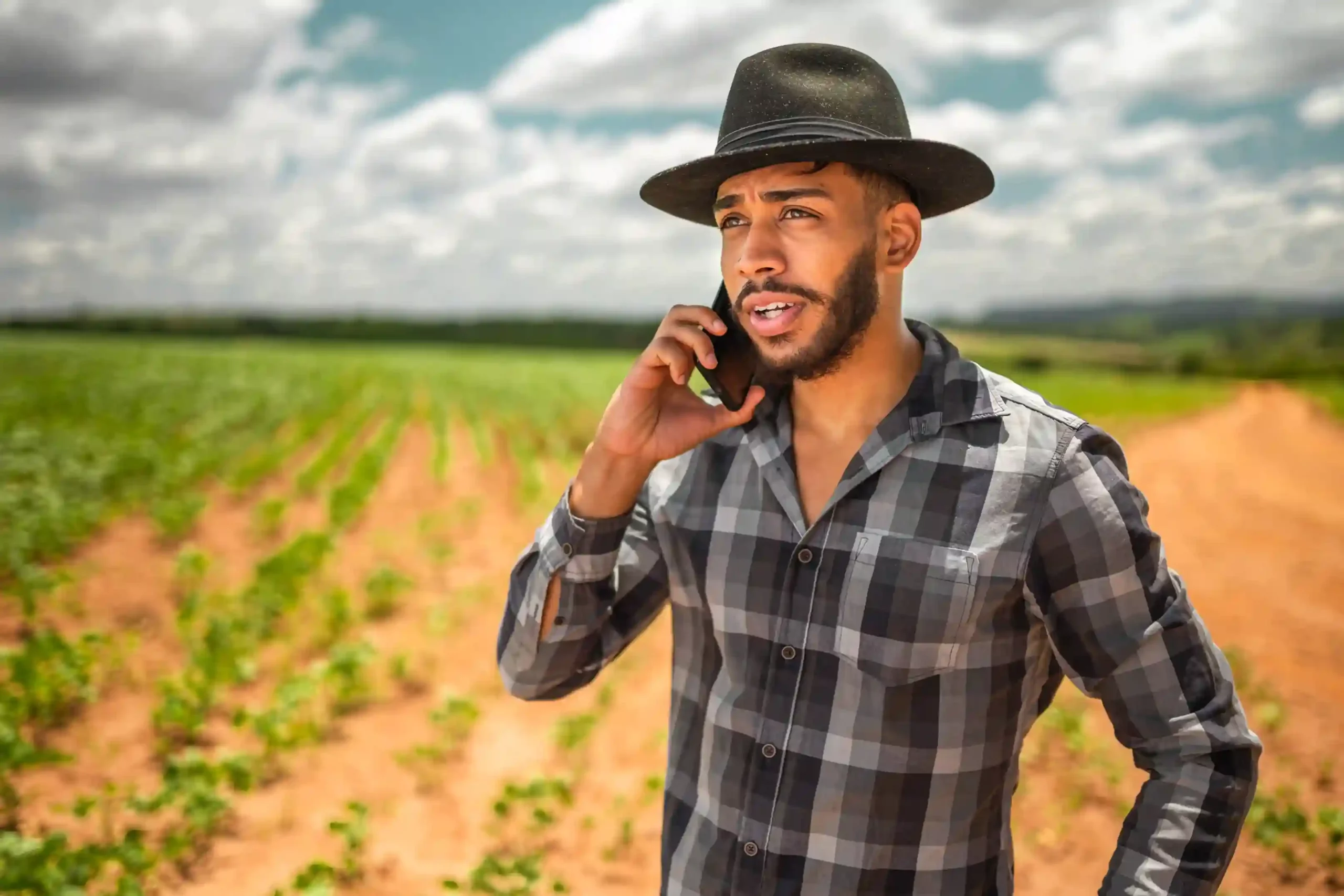 A farmer contacts an agricultural support line using a toll-free number, relying on a system designed to handle many similar inquiries at the same time. A farmer stands in the field speaking on his phone, confidently reaching a government department through a toll-free number that can handle high call volumes without delays.