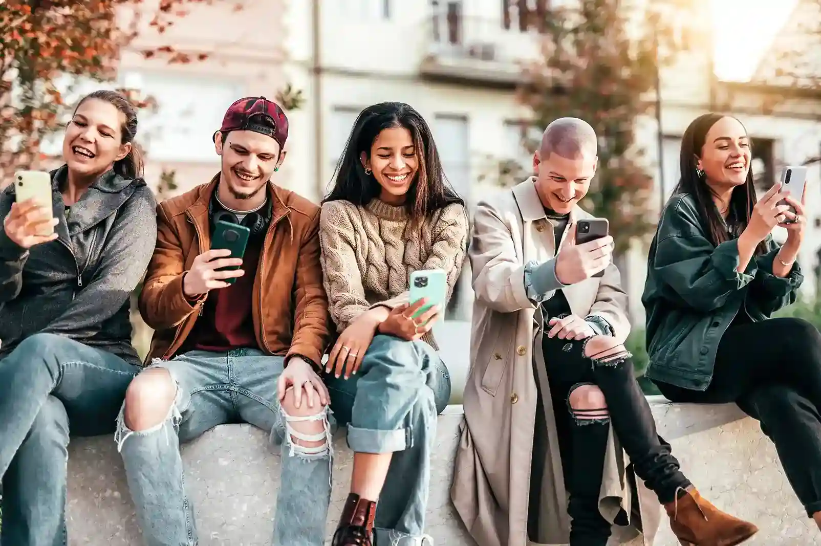 Friends smile as travel offers arrive on their phones at the same time, showing how shortcode messaging supports large audiences without missing responses. A group of people relax outdoors while checking their phones, each receiving a timely SMS sent through a shortcode-enabled campaign designed to handle large-scale responses.