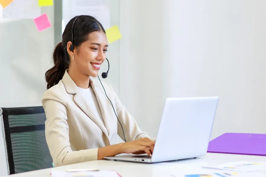 Indosoft interface enabling a call agent to dial and automate workflows instantly after contact import. Support agent smiling at her laptop as Indosoft makes imported contacts ready for immediate use.
