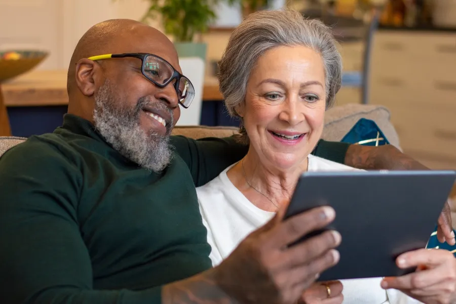 Smiling senior couple viewing their tablet as Indosoft simplifies CRM and system transitions for them. Senior couple happily using a tablet supported by Indosoft’s seamless CRM and system migration capabilities.