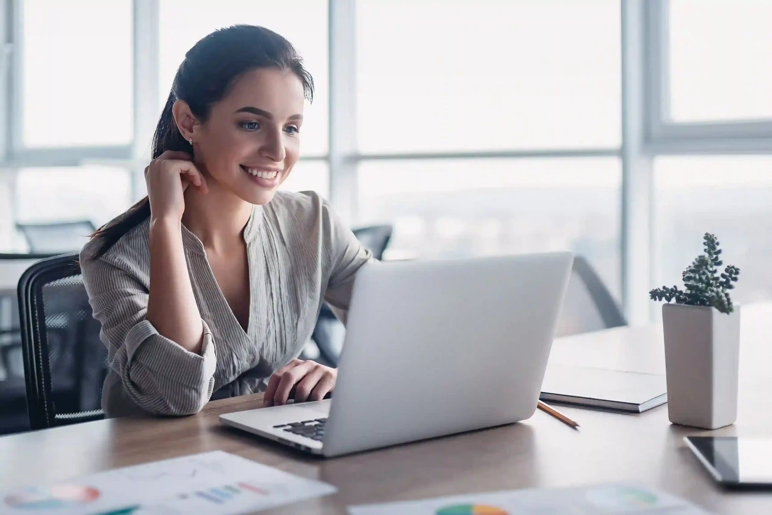 A sales professional smiles while checking account details on her laptop and initiating a quick callback, demonstrating how faster follow-ups keep momentum strong. An agent reviews customer notes on her laptop and places a follow-up call immediately, showing how Click to Call removes delays between tasks and outreach.