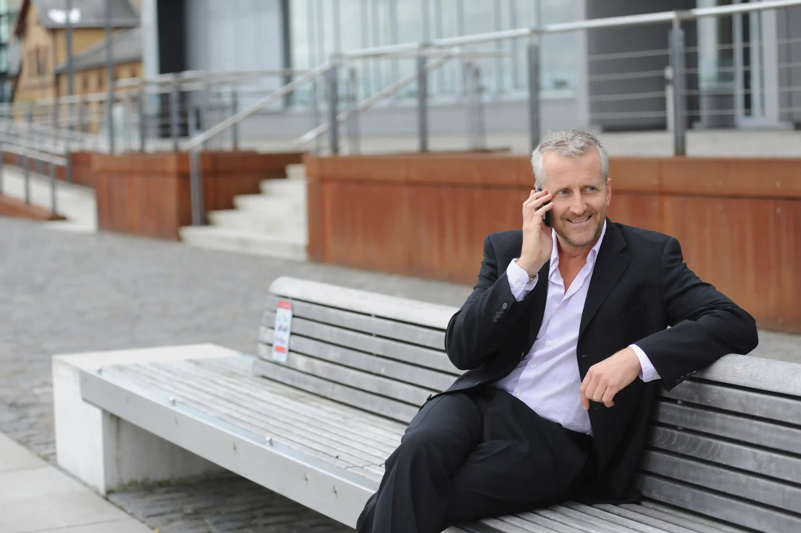 An executive handles an incoming call with ease, reflecting how IVR provides a standardized call experience that feels familiar and dependable every time. A business professional calmly takes a call outdoors, experiencing the same clear and predictable IVR call flow that guides every caller with consistent steps.