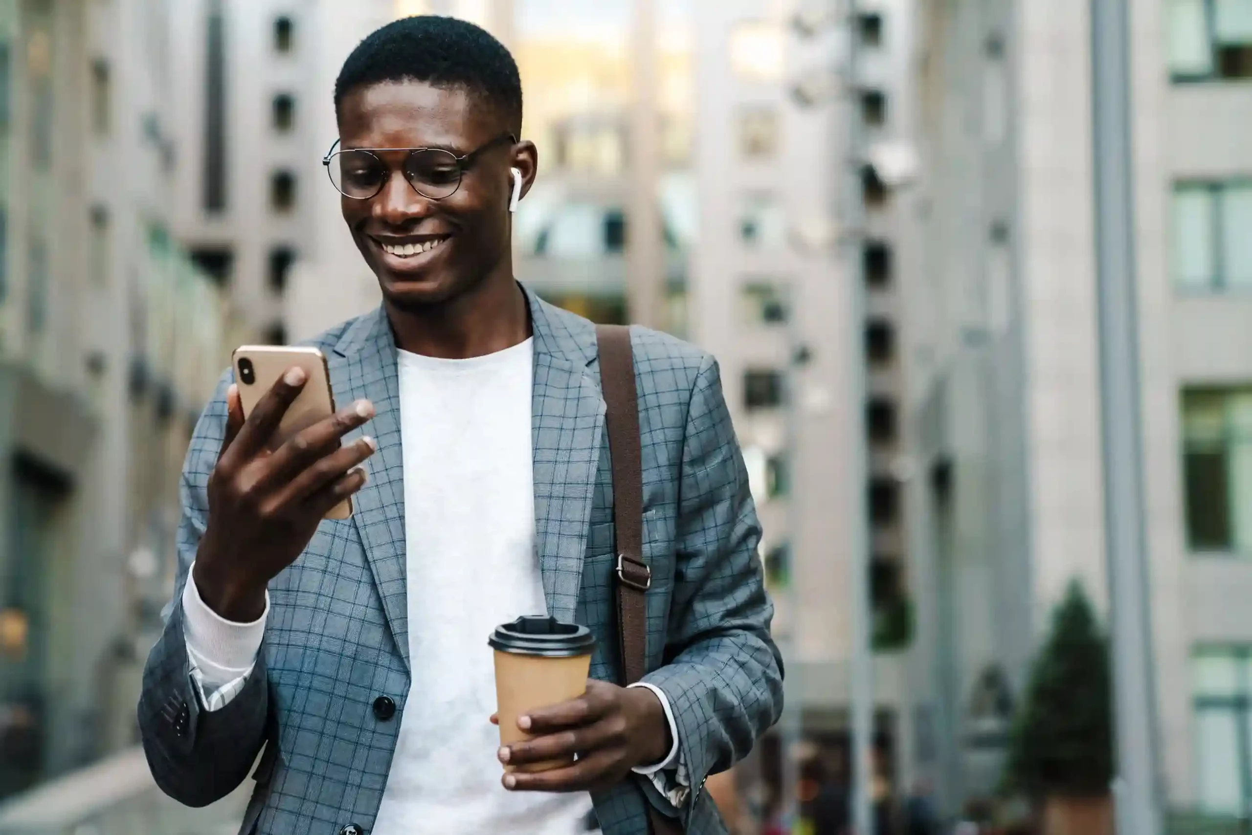 While walking through the city with coffee in hand, a professional reviews a concise SMS update that feels useful rather than disruptive. A business professional smiles while checking his phone on the way to work, noticing that only relevant SMS updates reach him instead of frequent generic messages.