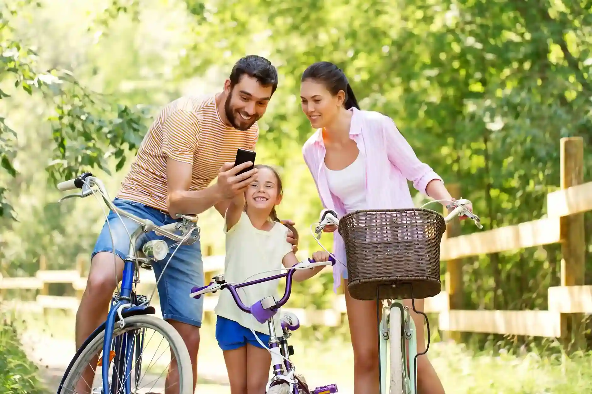 Parents and a child sharing a phone moment outdoors, reflecting how separate teams operate independently while remaining clearly identified through dedicated outbound numbers. A family enjoying time together on bicycles while coordinating plans on a smartphone, symbolizing how different teams and locations use distinct phone numbers while staying connected under one organization.