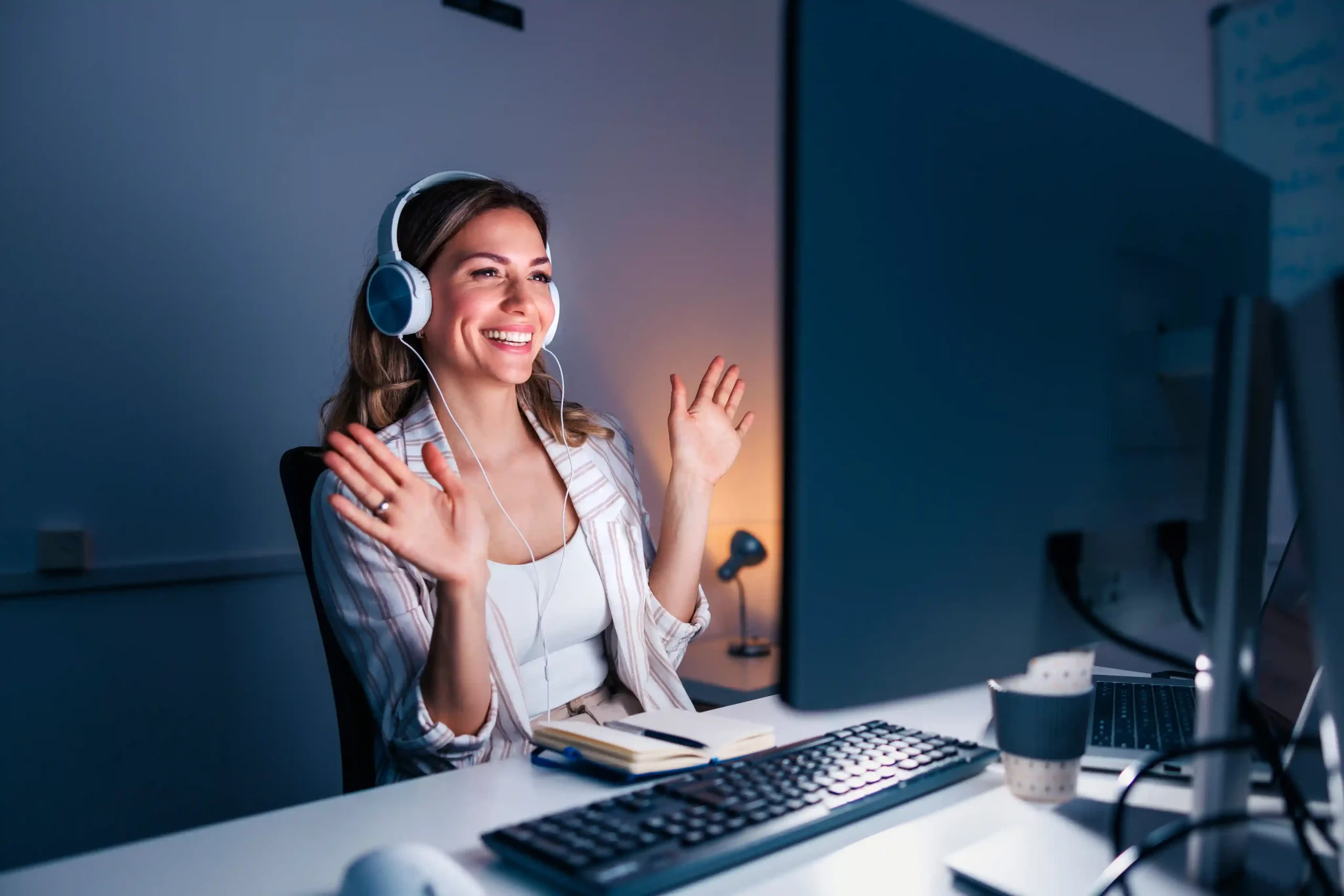A contact center agent actively engages multiple participants on a live call, ensuring questions are answered once instead of repeated across transfers. An agent wearing a headset smiles and gestures during a live conference call, resolving a customer issue by bringing everyone into one focused discussion.