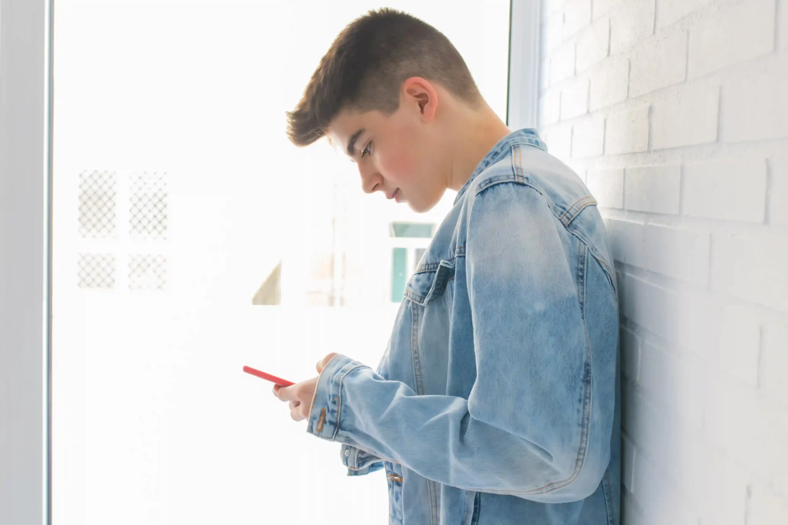 Leaning against a wall, a user calmly checks a message knowing SMS filters organize conversations before they reach the team. Standing by a window, a young professional reviews an SMS on her phone while organized filtering keeps conversations structured and easy to follow.