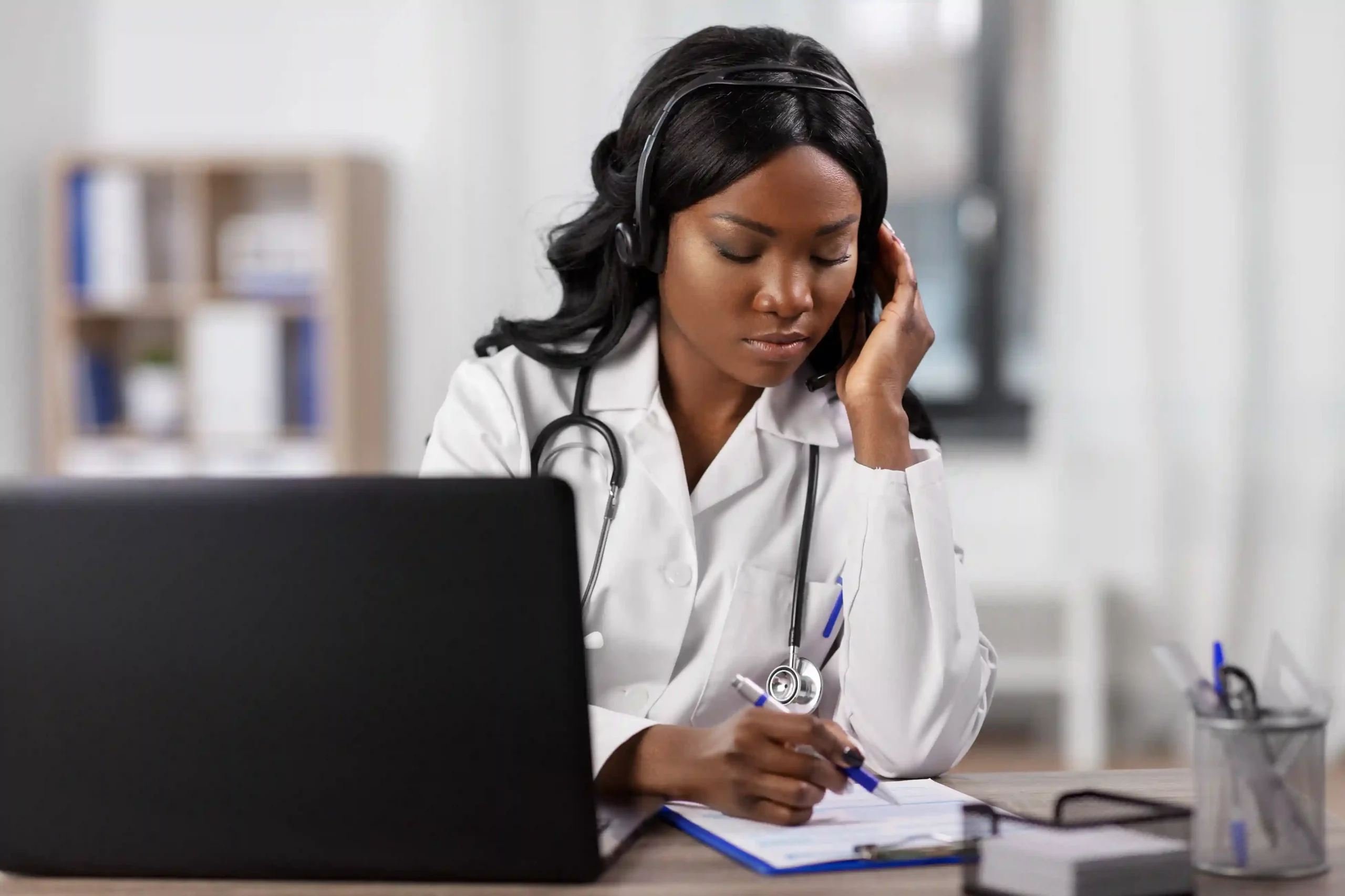 While reviewing notes, a healthcare professional receives a high-priority call alert and shifts focus instantly to handle an urgent incoming request. A doctor pauses documentation after receiving a priority call notification, recognizing the urgency and responding immediately to address a critical patient concern.