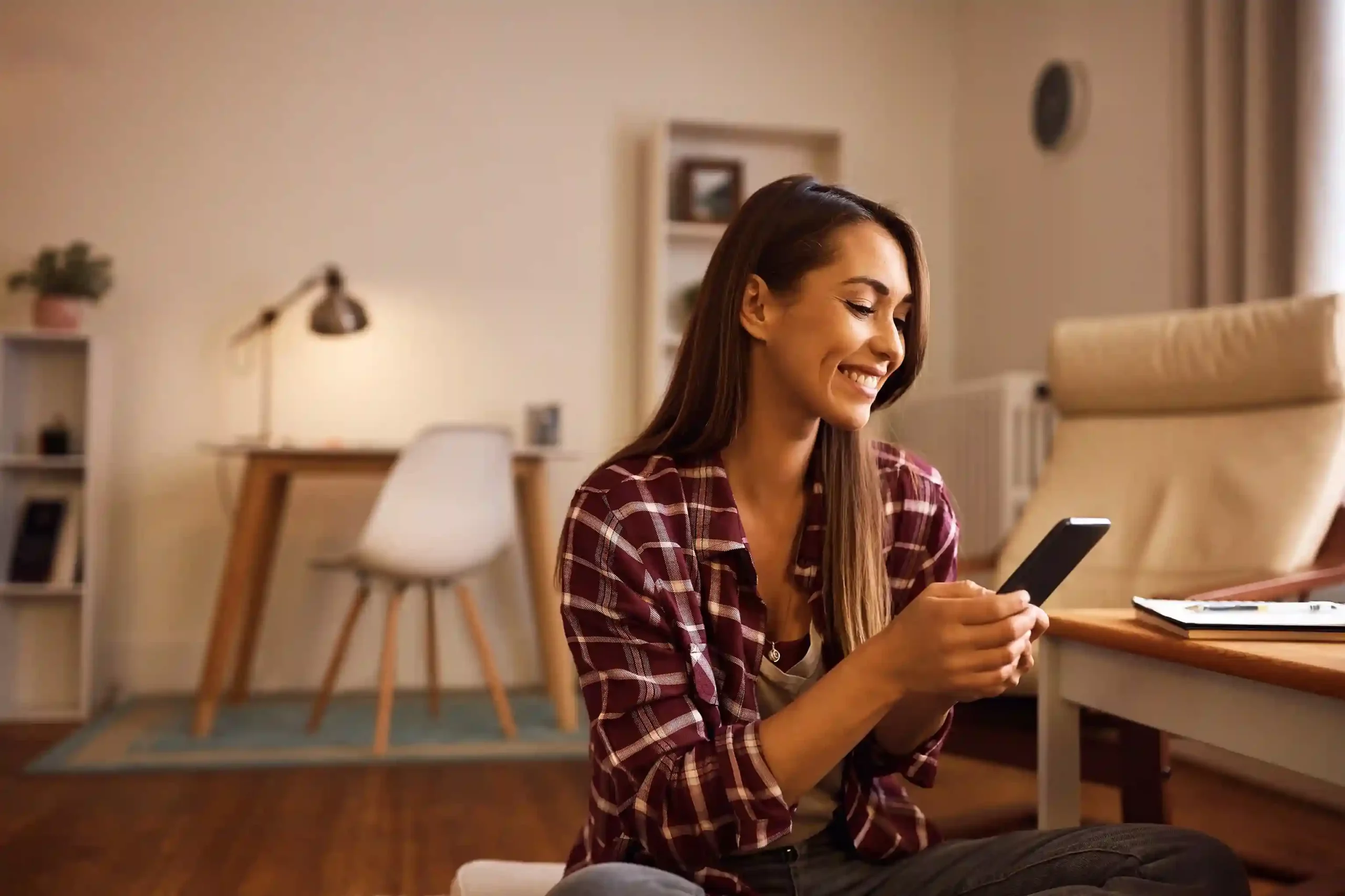 While working comfortably from home, an agent notices an incoming call on her phone, reflecting how Ring All Devices keeps critical calls from going unanswered Checking her phone at home, a professional catches an important incoming call in time, showing how Ring All Devices prevents missed calls even when one device is unattended.