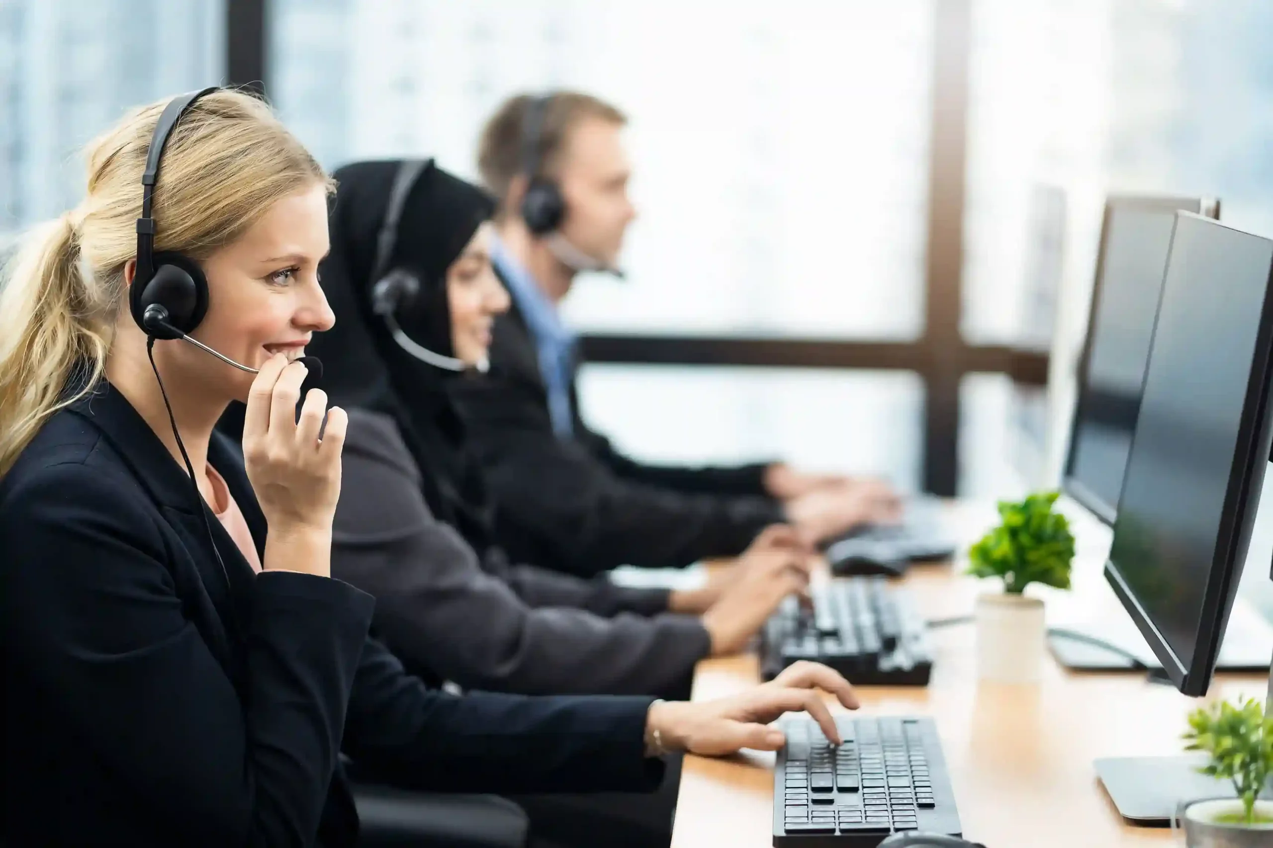 Focused on their screens, agents manage incoming calls smoothly while Ring All Devices ensures every connected device is ready without extra configuration Seated at their workstations, contact center agents handle calls seamlessly across multiple screens, showing how Ring All Devices removes the need for manual device switching.