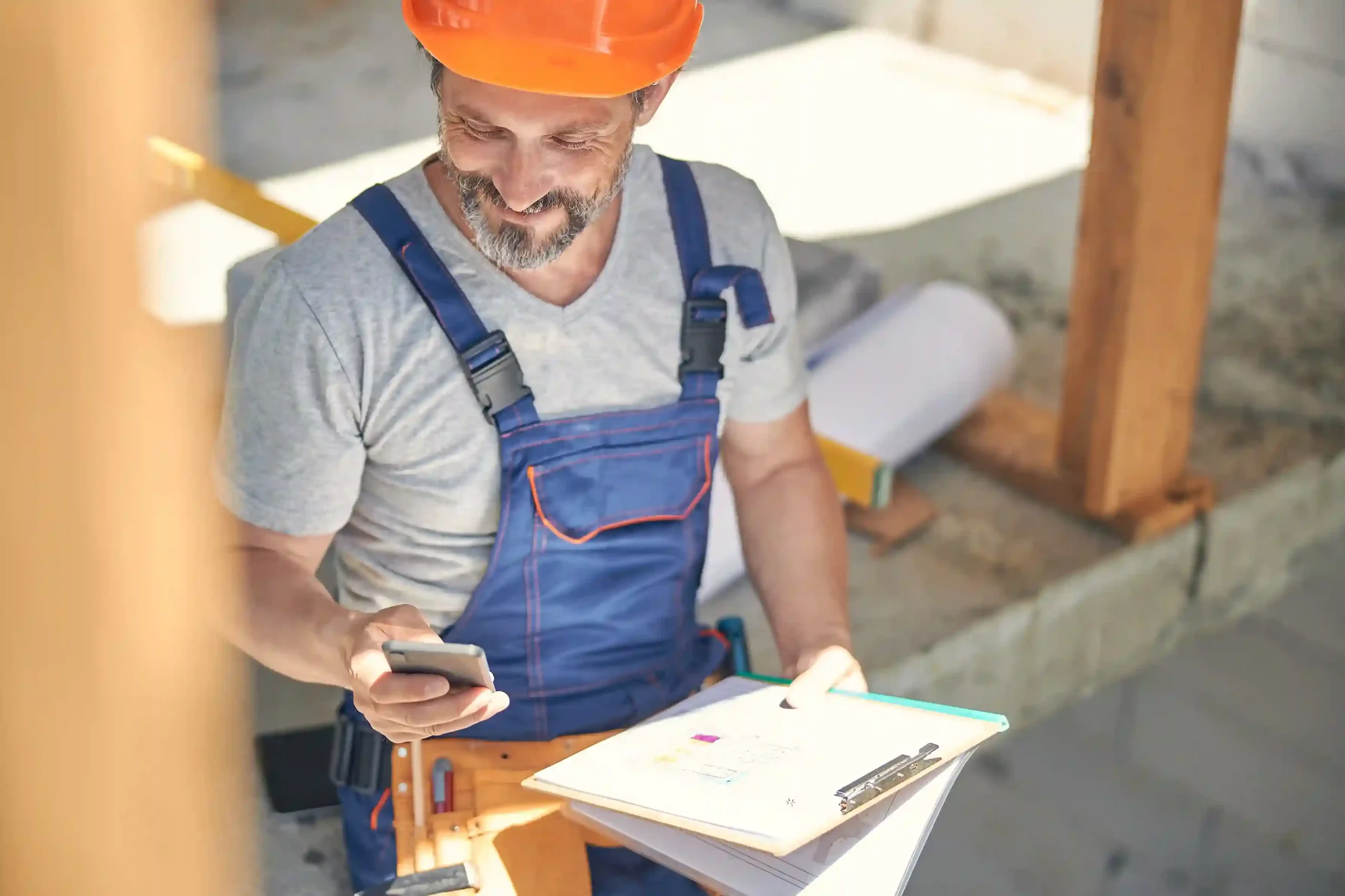 While reviewing plans at a construction site, a worker reads an SMS that arrives at the right time because message rules control which updates are allowed through. A construction worker pauses on-site to check an SMS on his phone, receiving only essential updates that have been filtered based on predefined message rules.