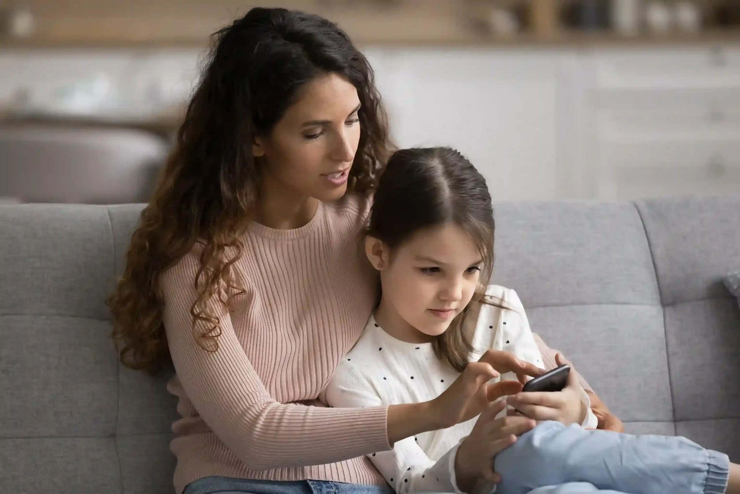 A caregiver and child focus on a single message thread together, reflecting how agents use a centralized inbox to stay aligned on customer communication. A parent helps a child review a message on a phone, mirroring how support teams rely on one shared workspace to keep conversations visible and consistent.