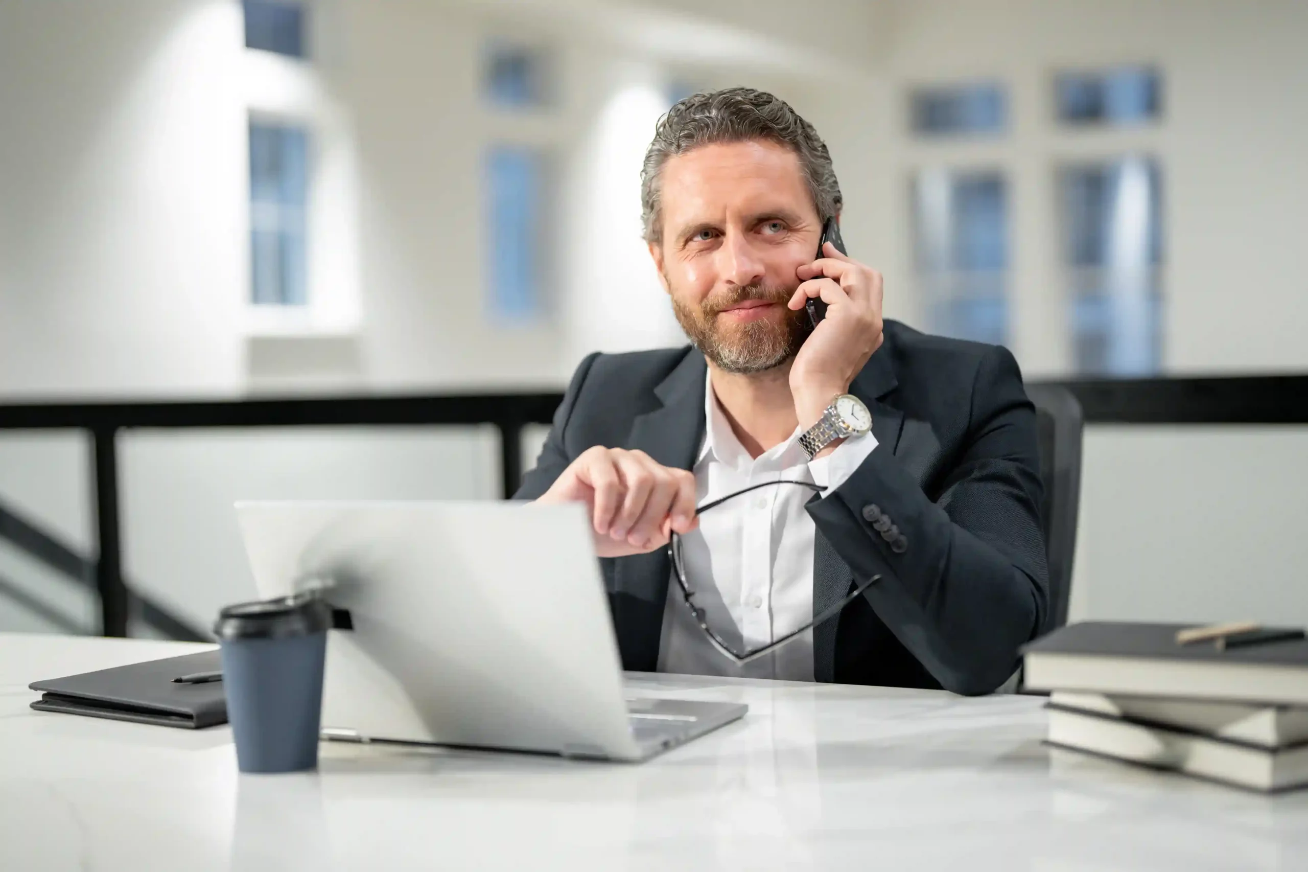 A manager confidently handles a call at his desk, supported by a structured extension system that directs conversations to the right teams without confusion. A business professional reviews information on his laptop while taking a call, reflecting how extensions are organized by role and department to keep communication clear.