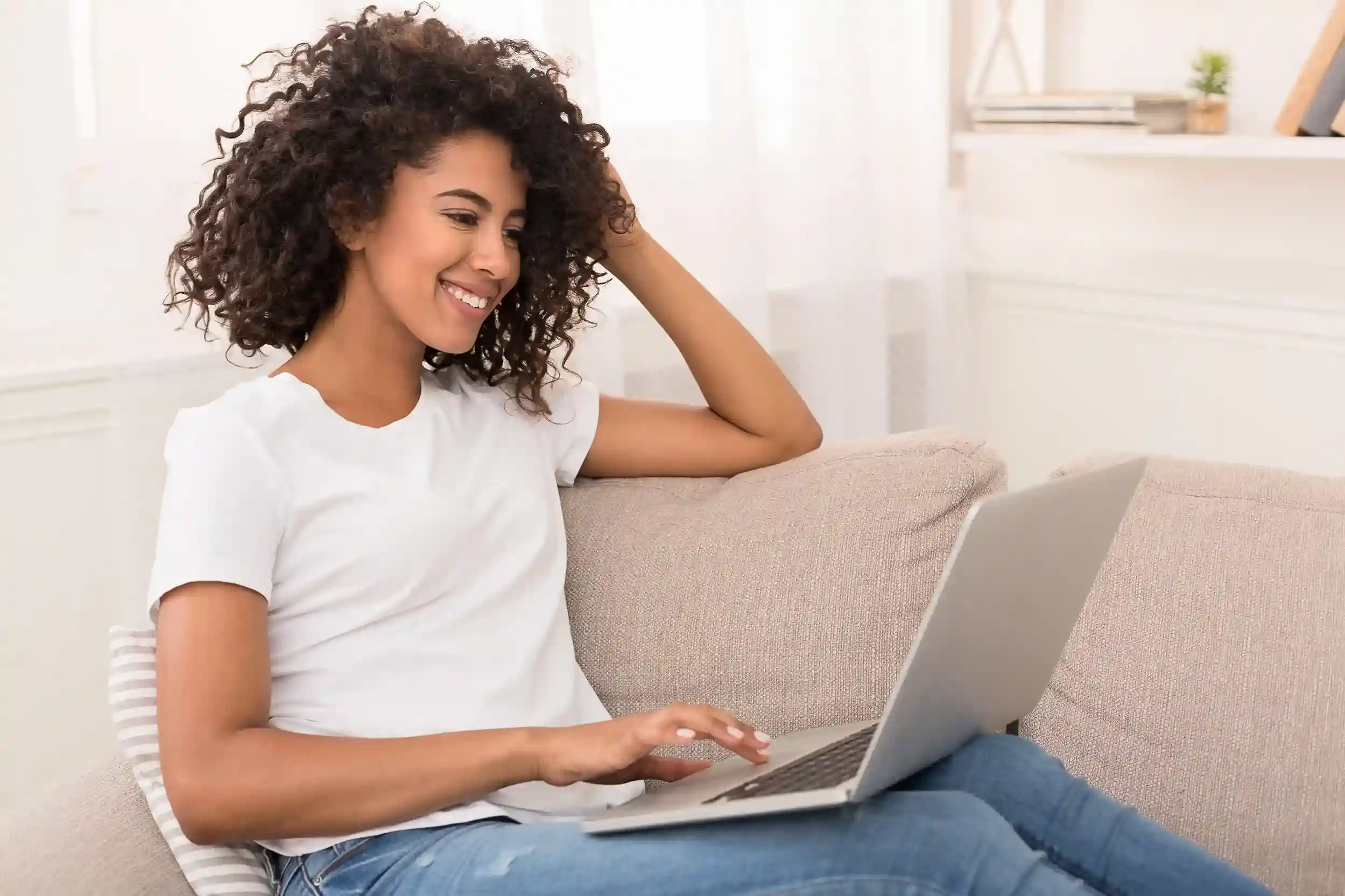 A professional checks her laptop and smiles as a voicemail arrives in her email, using Indosoft to stay connected to callers even when away from the desk. An employee relaxes on a couch while reviewing a newly received voicemail in her email inbox, using Indosoft to stay informed without logging into a phone system.