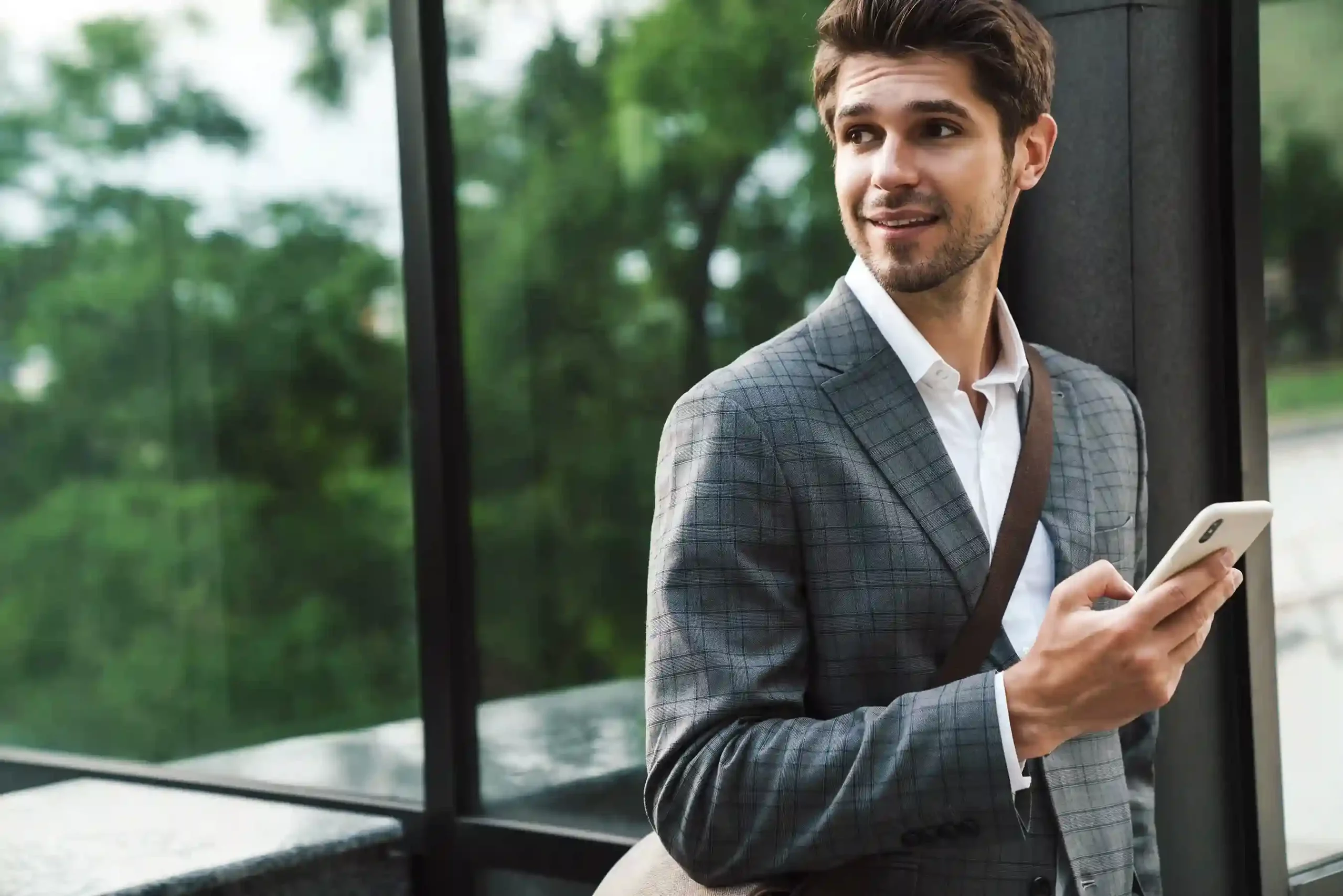 A business professional pauses during his commute to manage customer communication, supported by number sharing that allows teammates to collaborate from one shared phone number. A professional checks messages on his phone while on the move, relying on number sharing so multiple team members can respond from the same business number without losing accountability.