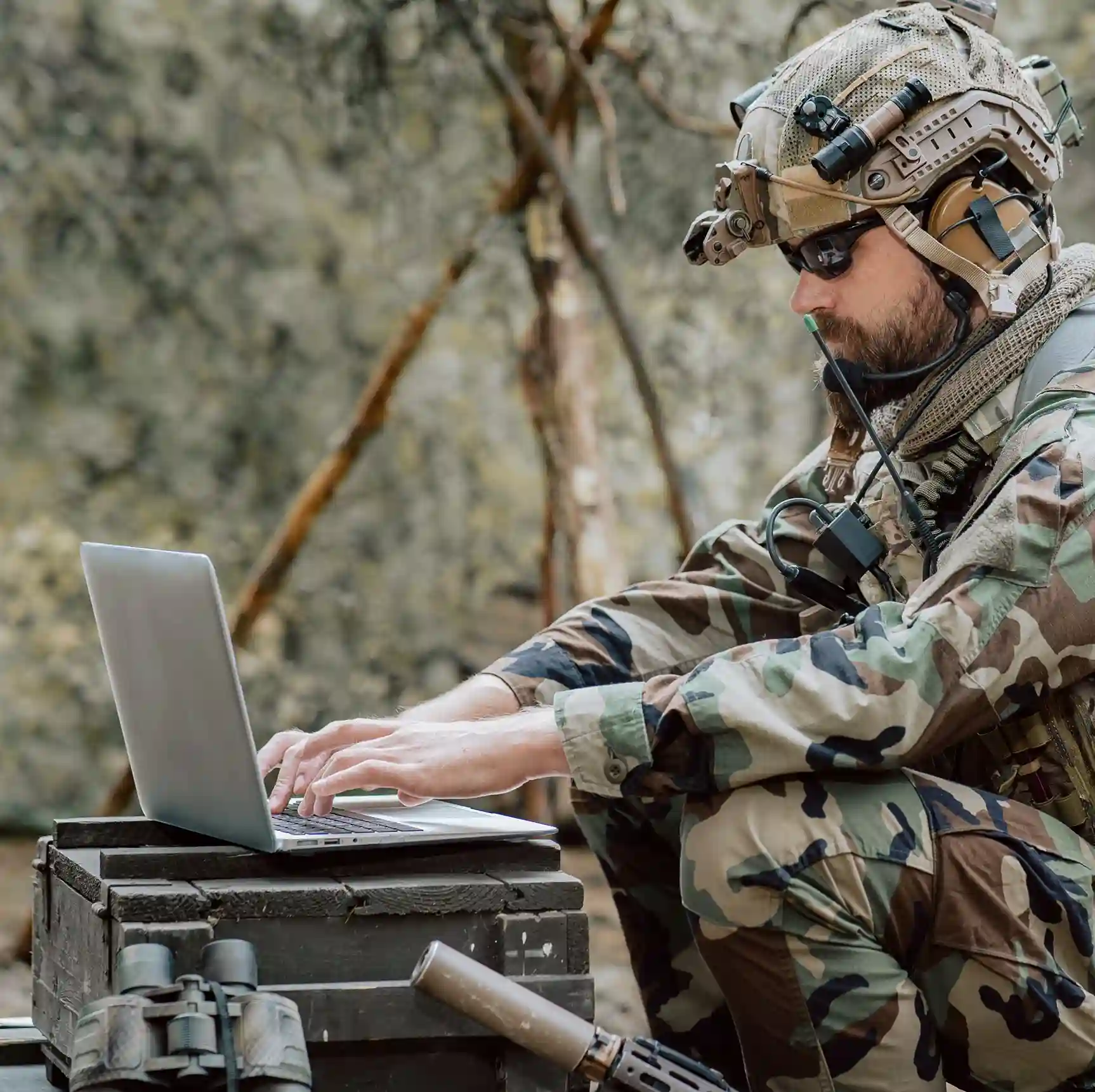 Armed forces operator with communication equipment connects to the central command through Indosoft’s secure military communication system. A field soldier in full tactical gear manages secure communications on a rugged laptop in a remote environment, coordinating mission updates through a protected contact center system that keeps military teams connected in real time.